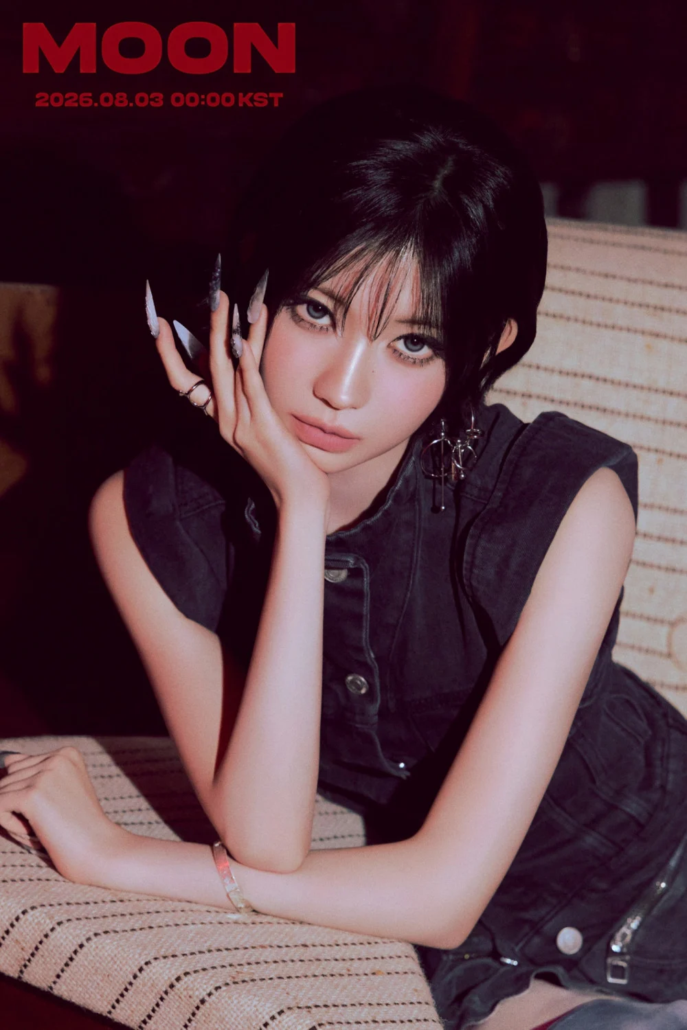 Asa leaning against a sofa wearing bold accessories and nails