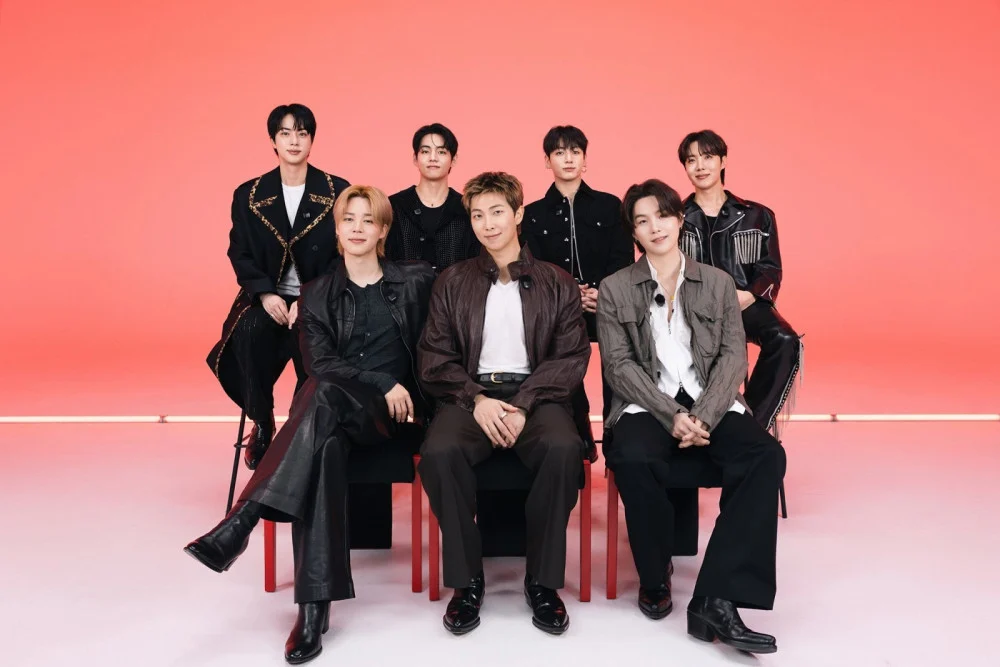 BTS members celebrating chart success beside Billboard Hot 100 graphic