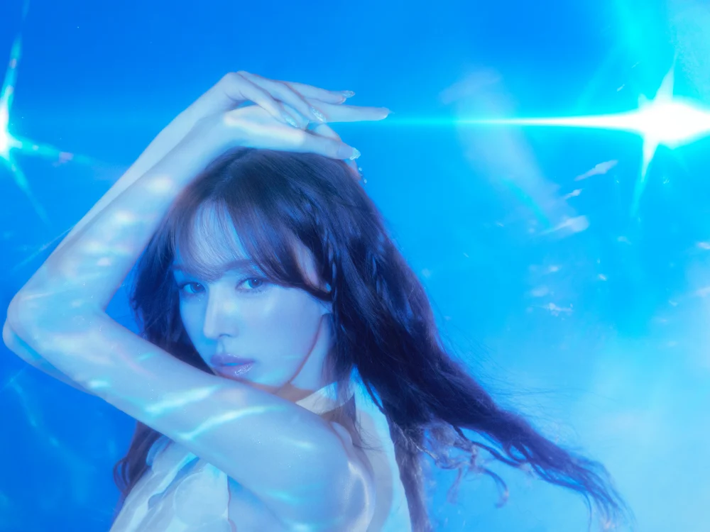 full-body pose framed by flowing hair and aquatic hues