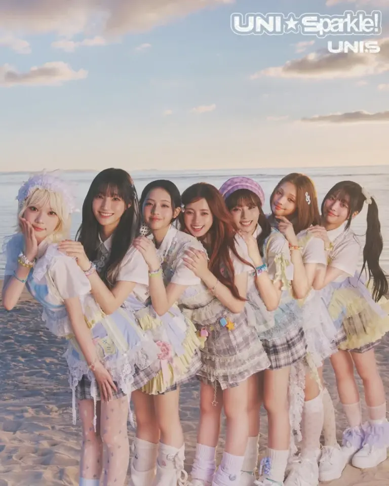 UNIS eight members posing with UNI☆Sparkle! album and sparkly outfits