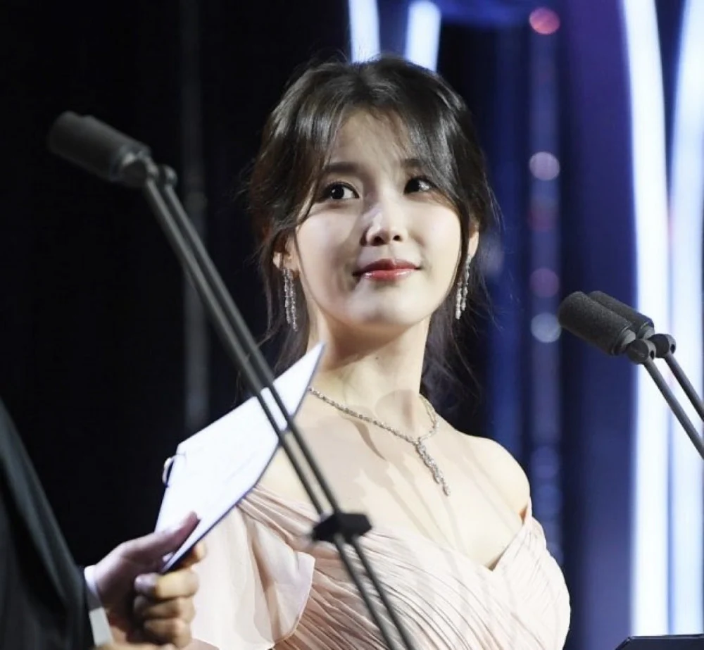 IU smiling onstage while presenting award alongside Ju Ji Hoon