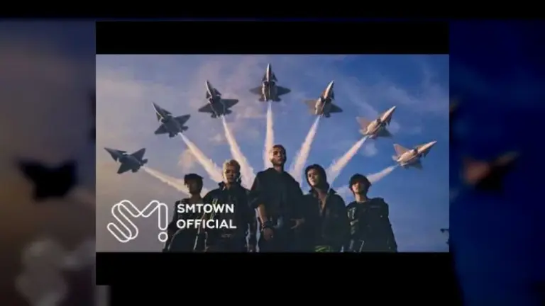 NCT 127 members in cockpit wearing pilot gear and helmets