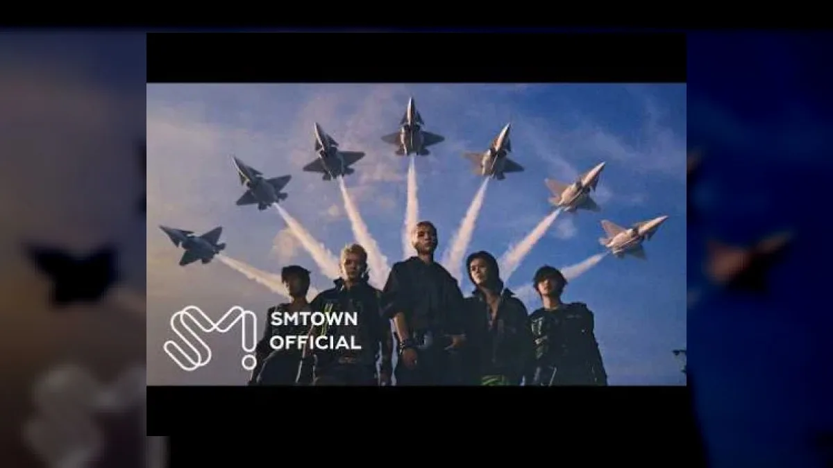 NCT 127 members in cockpit wearing pilot gear and helmets